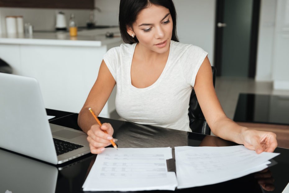 Concentrated woman analyzing home finances while looking at documents