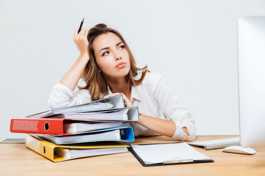 Pensive businessman sitting at the office desk and holding pen